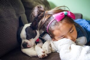 girl sleeping beside a dog on the sofa